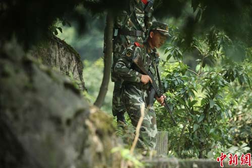 　圖為武警官兵提著槍支搜尋犯罪嫌疑人蹤跡。